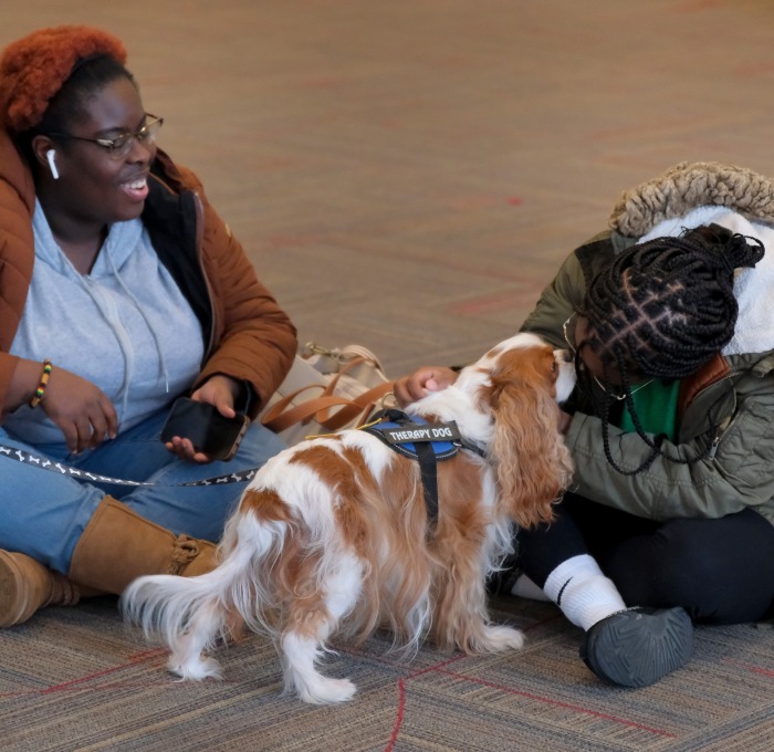 Female students with therapy dog in Hammond Main Lounge