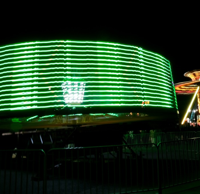 Spinning carnival rides with green and gold lights