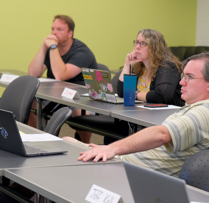 Two male and one female AP student listening intently in a classroom