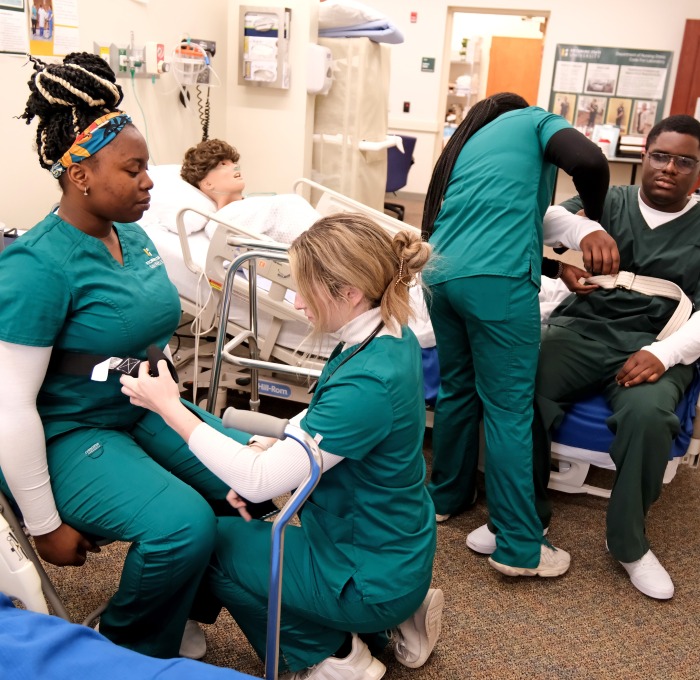 Nursing students in patient transfer lab preparing each other