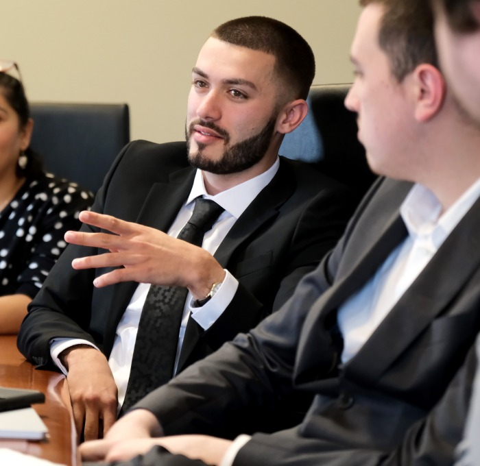 Students in suits competing in discussion at table