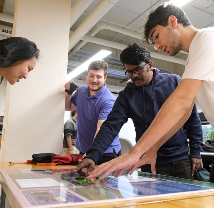 Engineering students at competition looking at poster on table