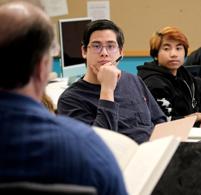 Male students listen to teacher in classroom 