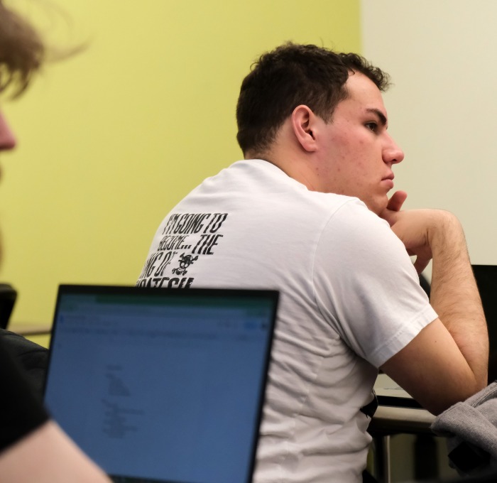 Two male students from behind in front of their laptops