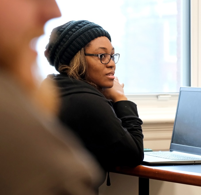 Student with hat and laptop in classroom