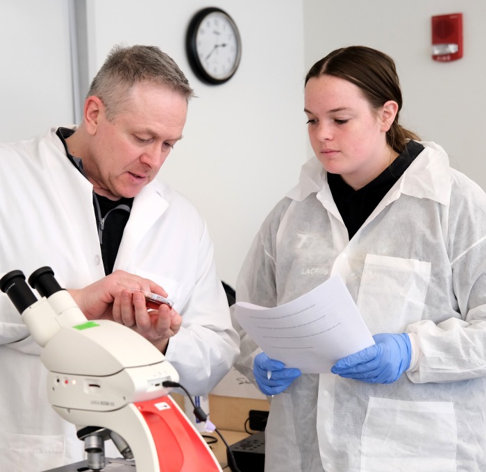 Student and teacher in white coats in microbiology lab