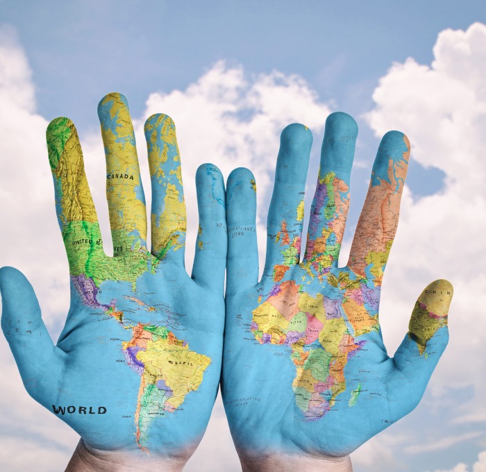 Helping hands with the world across them in the clouds
