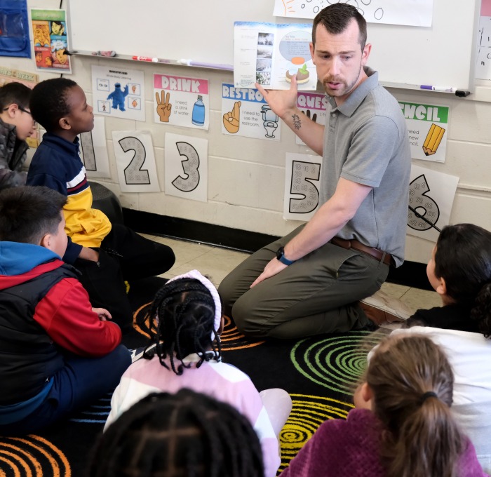 Dustin Halterman in classroom reading to a group of students