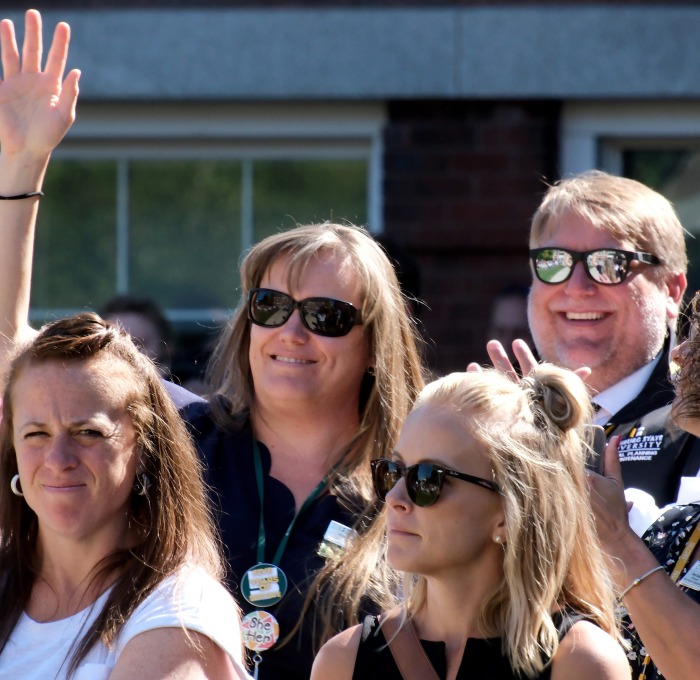 Smiling staff on the quad waving at the state of the university address