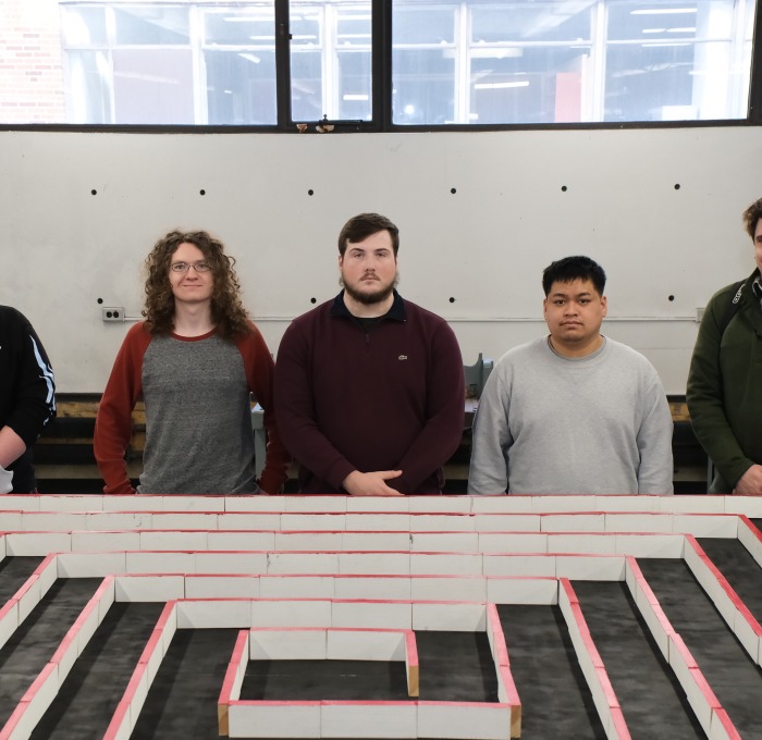 Engineering students in front of their micro mouse winning project