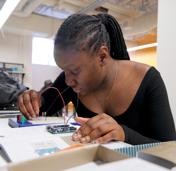 Student working on electronics at table in classroom