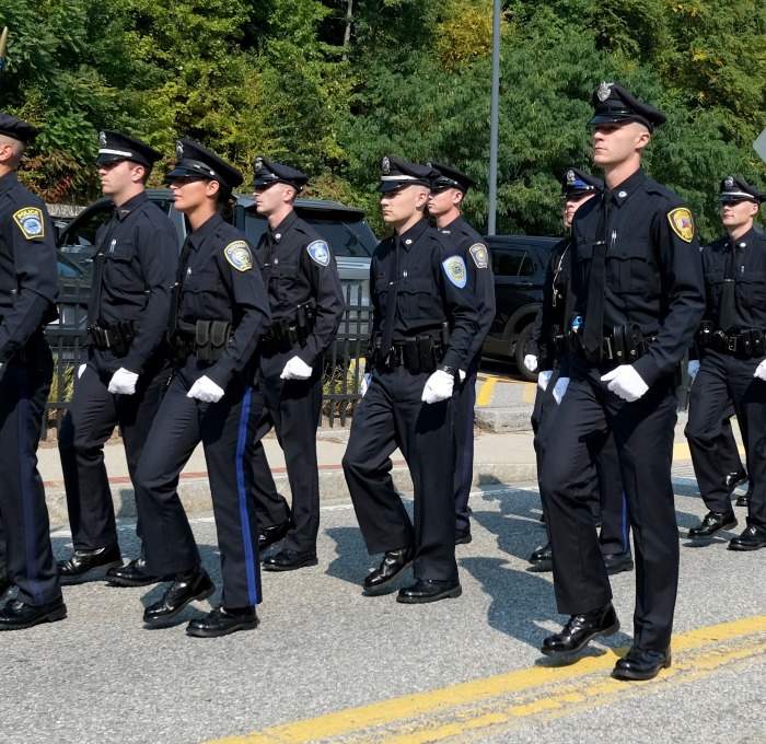 ROC graduating class marching down the street with police car and instructors behind