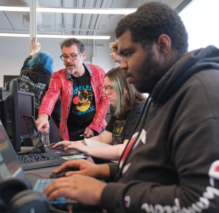 Game design workshop students working on computers with Jeff Warmouth advising