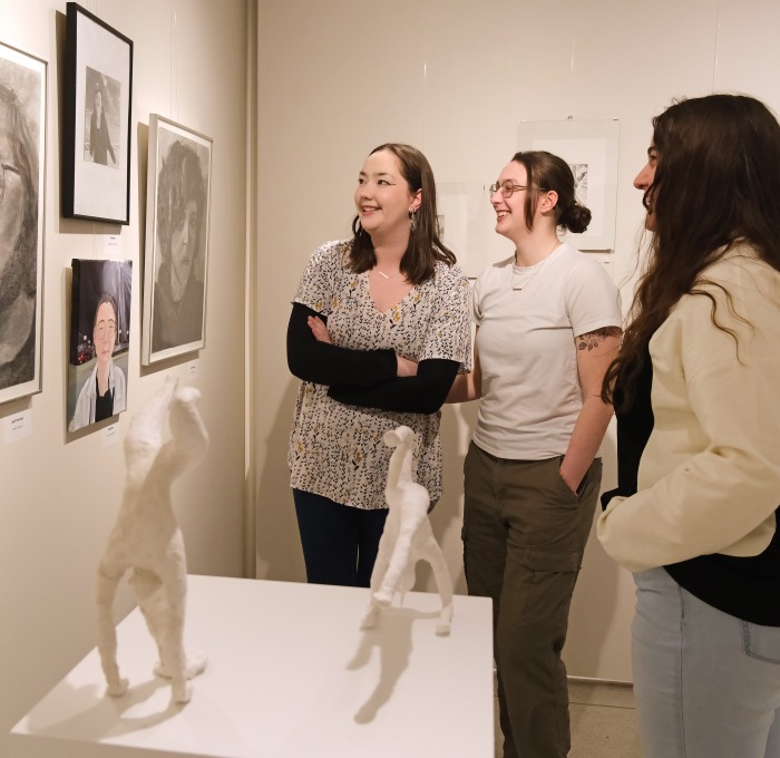 Female students smiling while looking at art in the gallery