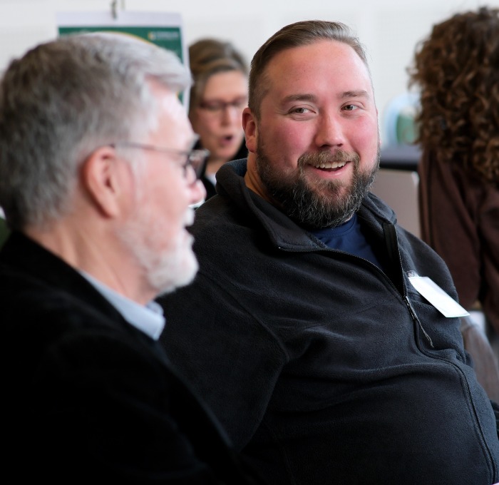 Smiling male student looking and talking with Michael Greenwood