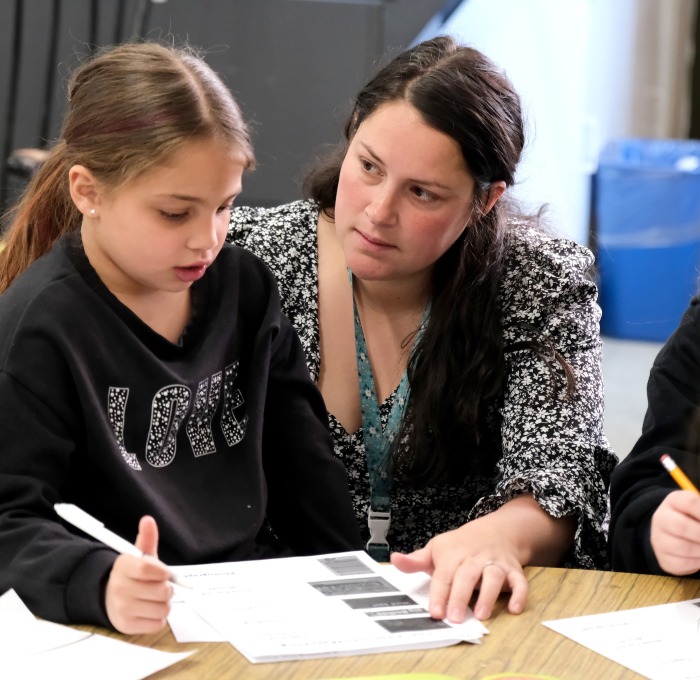 Student teacher at table looking at student