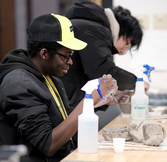 Three male students working with clay in the art studio