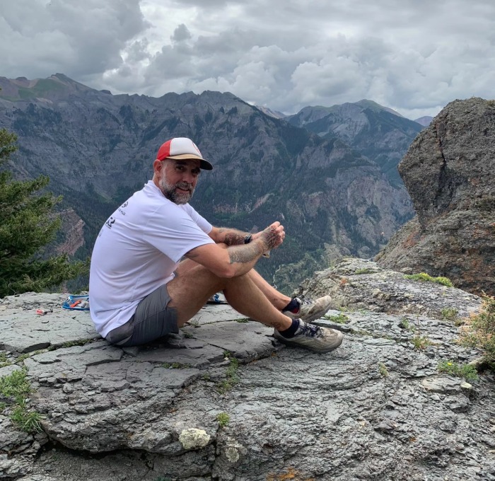 Jeff Godin sitting on the top of a mountain