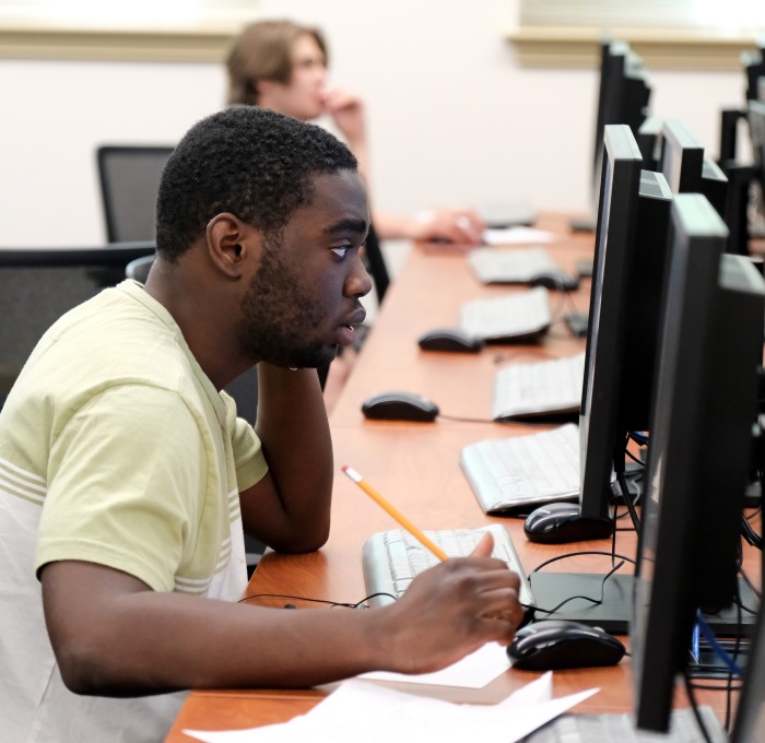 Male student at computer with pencil and paper
