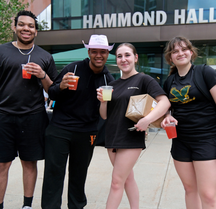 Male and female students in front of Hammond Hall with free drinks.
