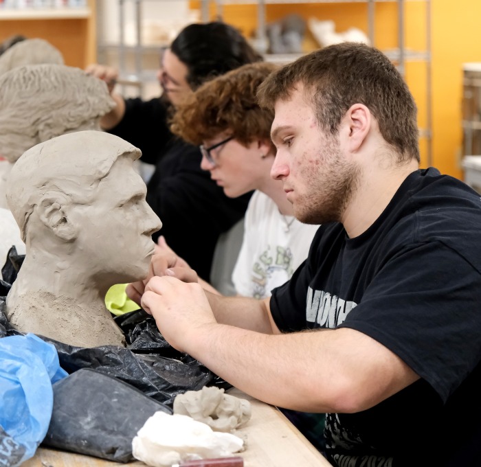 Students in art class creating head sculptures 
