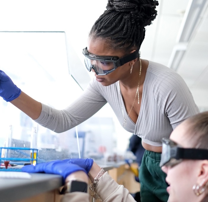Chemistry students filling test tubes in lab.