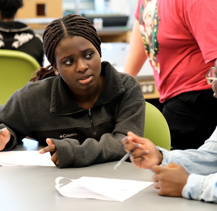 Middle school students talking at table.