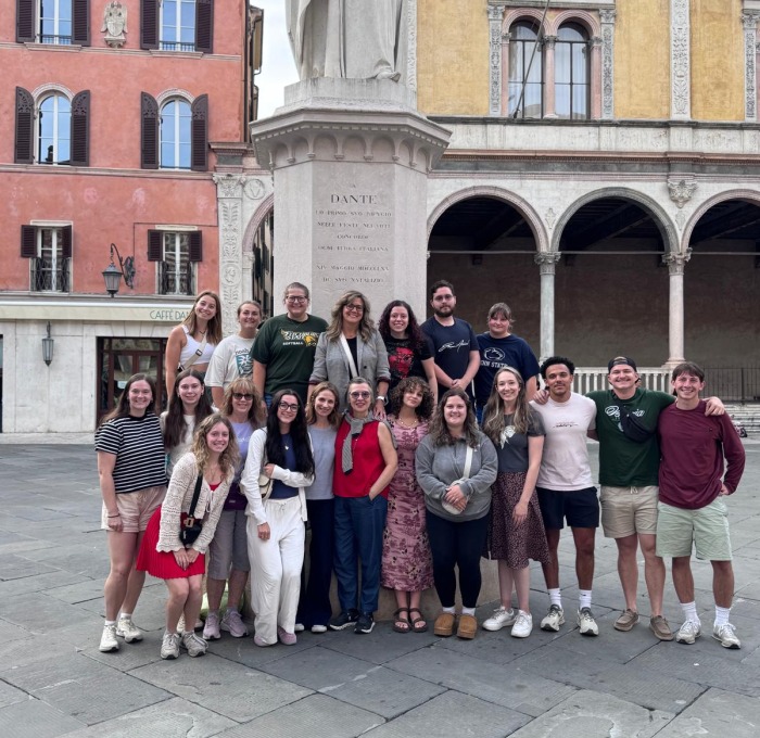 Students abroad in Verona, Italy outside amongst buildings and statue.
