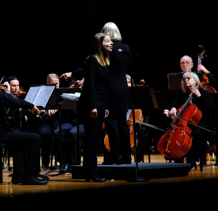 Female singer singing with the community band on stage in Weston Auditorium.