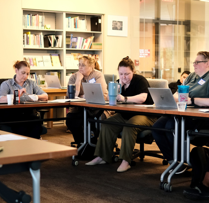 Faculty at tables with computers during development day.