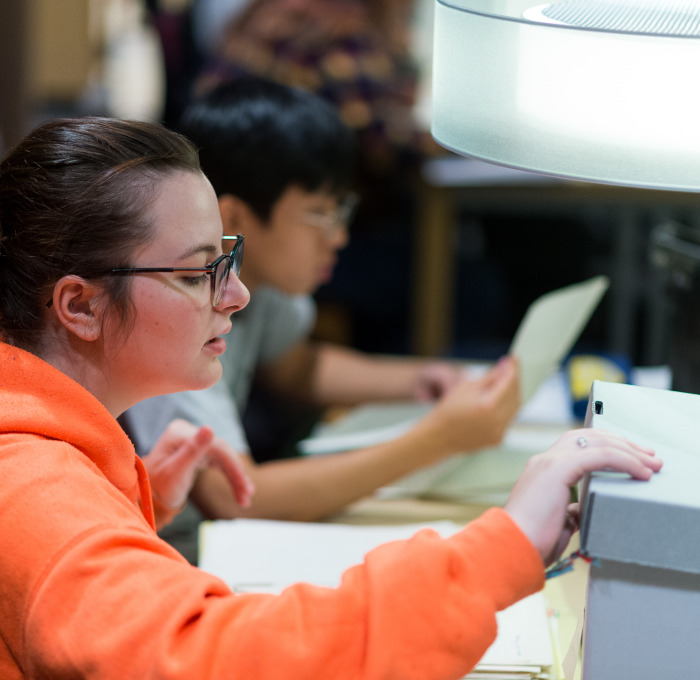 Female student in archives opening box.