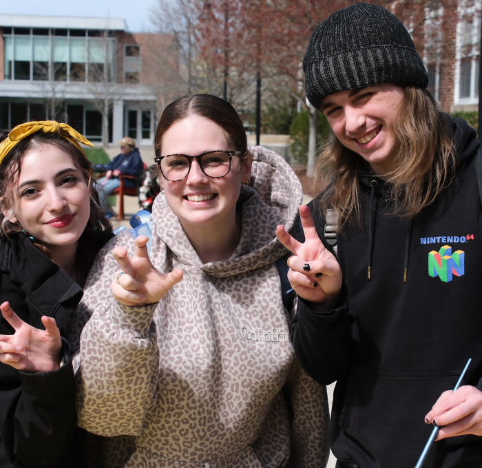 Smiling students with finger talons on the quad during Earth Day activities.
