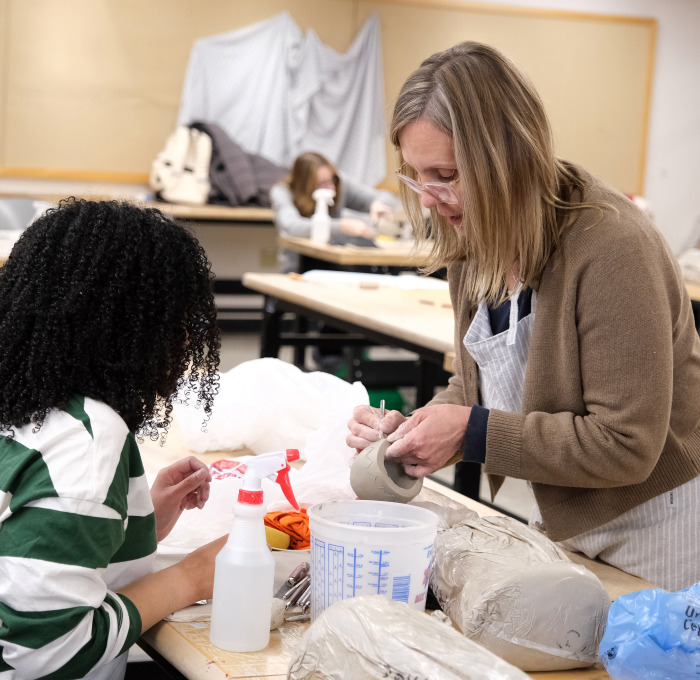 Student and teacher in visual arts pottery class.