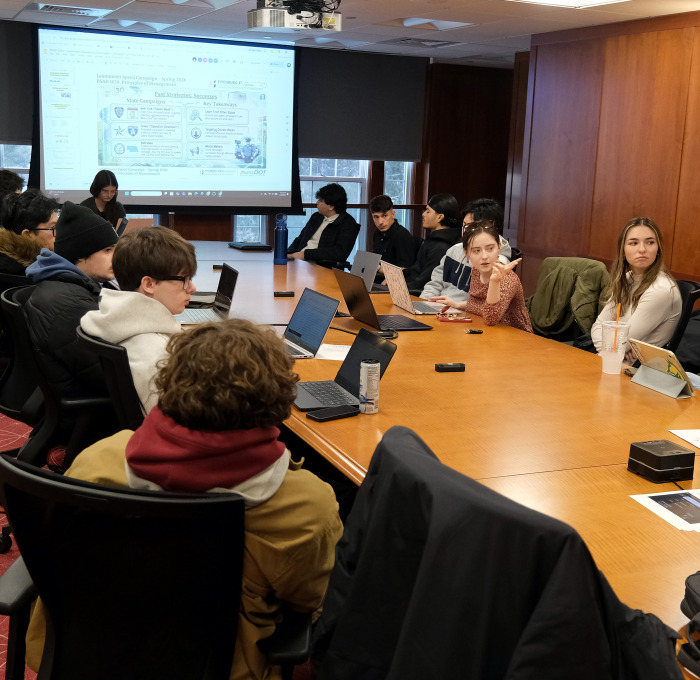 Business students at conference table with male presenting to class.