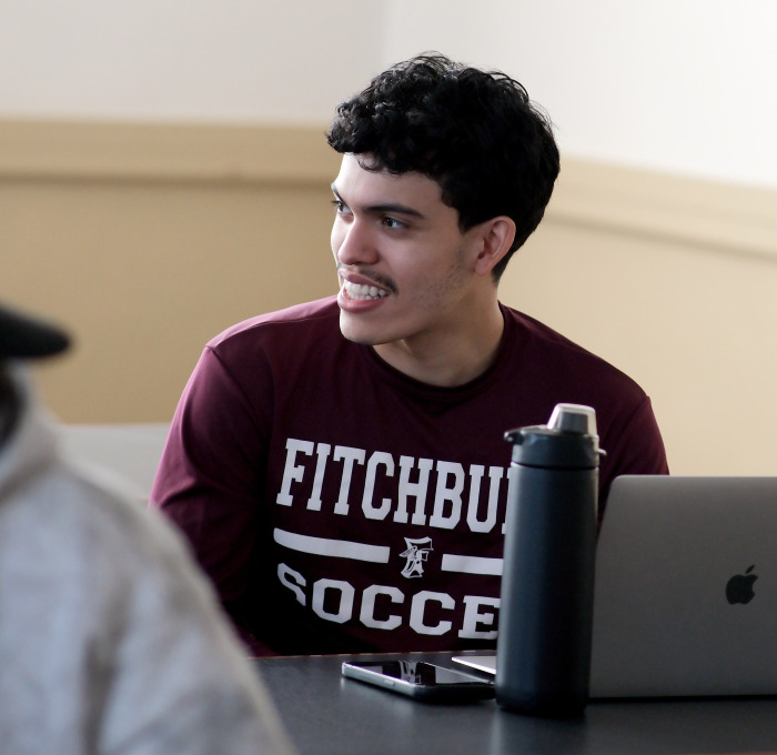 Smiling FHS student with laptop in classroom.
