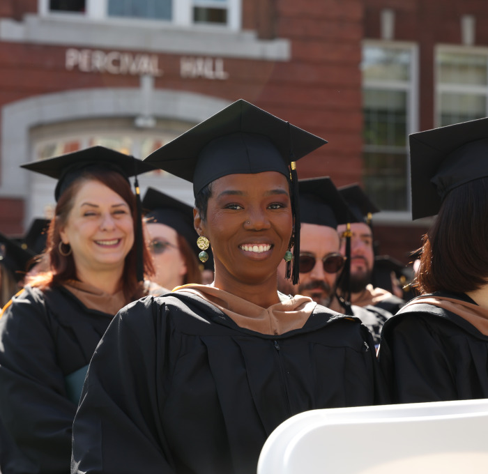 Smiling grad students on quad at commencement.