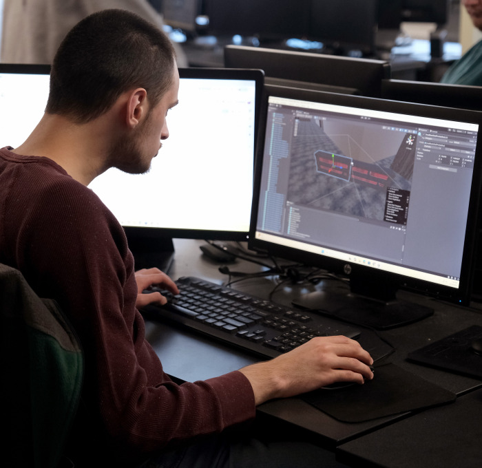 Male student working at computer with two screens.