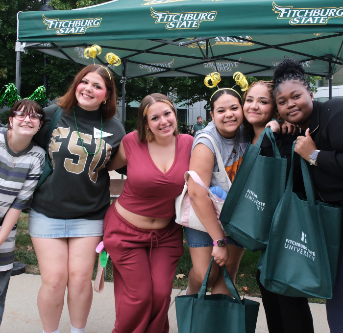 Group of smiling female students in front of tent at Rock the Block.