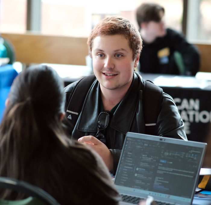 Student sitting at the Graduate Fair in Hammond Hall Main Lounge.