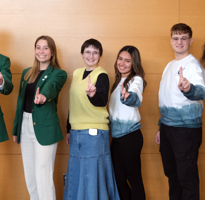 First generation students in main lounge holding up Number 1 with fingers.