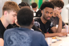 Male students talking at a table in Holmes.