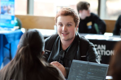 Student sitting at the Graduate Fair in Hammond Hall Main Lounge.