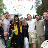 Family celebrates graduate with confetti outside on quad after ceremony