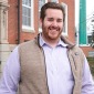 Matthew Costello '13 alum in front of Edgerly Hall with smokestack in background