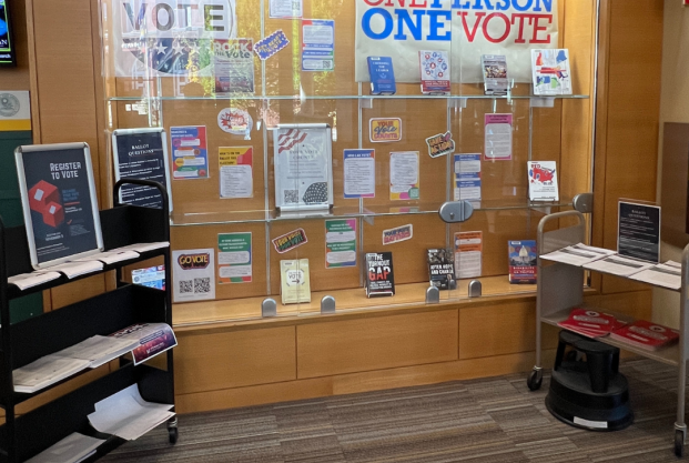 Display of voting related materials, including books and posters, inside a glass wall display case