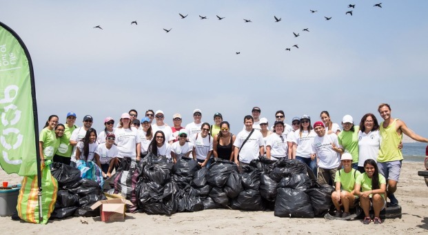 Group of LOOP volunteers on the beach picking up bags of plastics