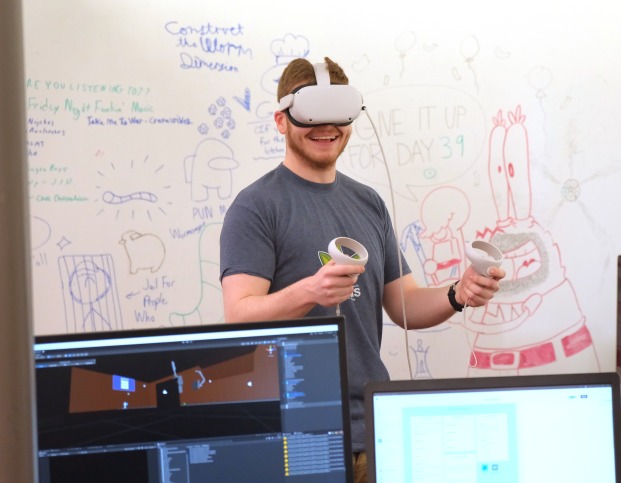 Male student using VR goggles and joysticks