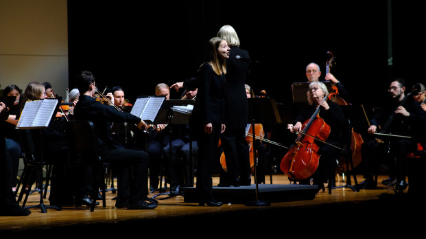 Female singer singing with the community band on stage in Weston Auditorium.
