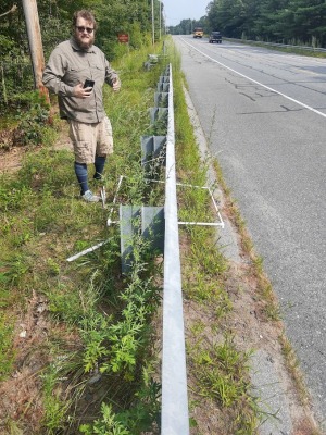 Cole Brunker on the side of the road assessing plants