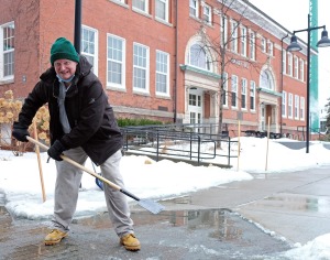 Maintainer breaking up ice on walkway in front of Edgerly